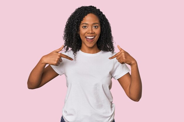 Une Afro-Américaine dans un studio étonnée montrant du doigt en souriant largement.