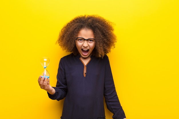 Afro-américaine, petite fille, contre, mur plat, tenue, a, horloge sable, minuterie