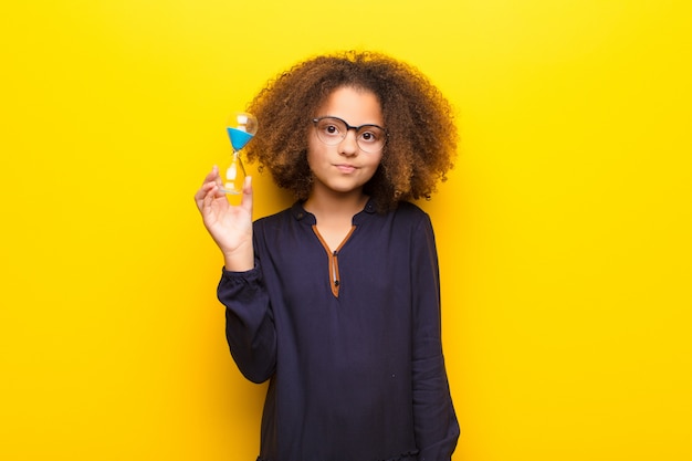 Afro-américaine, petite fille, contre, mur plat, tenue, a, horloge sable, minuterie