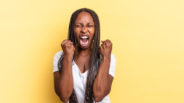 Afro black jolie femme criant agressivement avec un regard en colère agacé et frustré et des poings serrés se sentant furieux