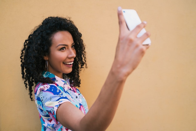 Afro femme prenant des selfies avec téléphone.