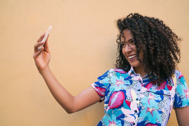 Afro femme prenant des selfies avec téléphone.