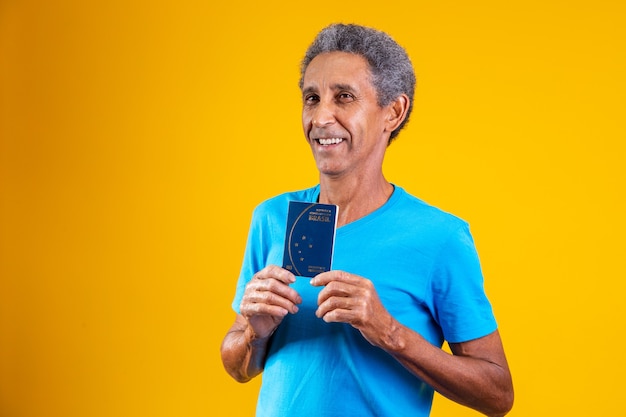 Afro homme âgé tenant un passeport brésilien dans les mains.