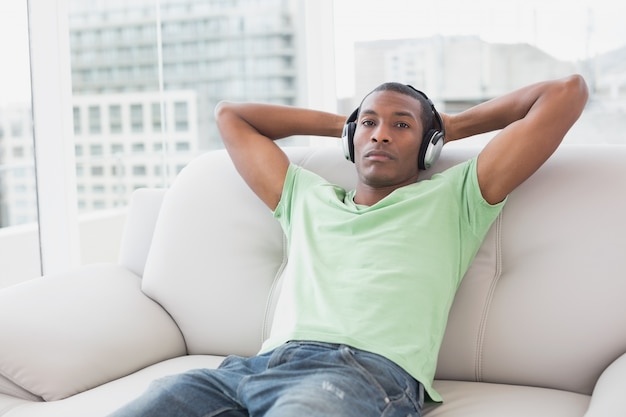 Afro homme détendu avec un casque assis sur le canapé dans la maison