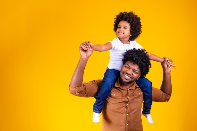 Afro père et fille sur fond jaune souriant et jouant le concept de la fête des pères