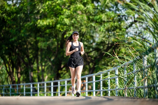 d'âge moyen Belle femme asiatique sportive marchant en plein air dans un parc souriant vivant un mode de vie actif et sain.