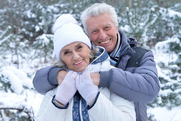 D'âge mûr heureux ensemble posant à l'extérieur en hiver