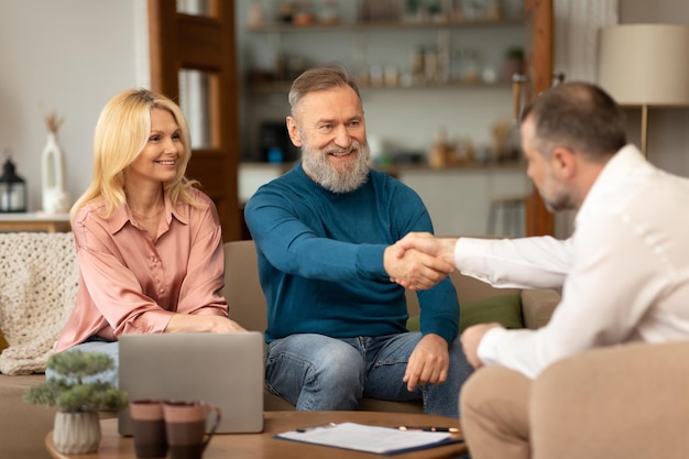 D'âge mûr serrant la main d'un agent immobilier professionnel à l'intérieur