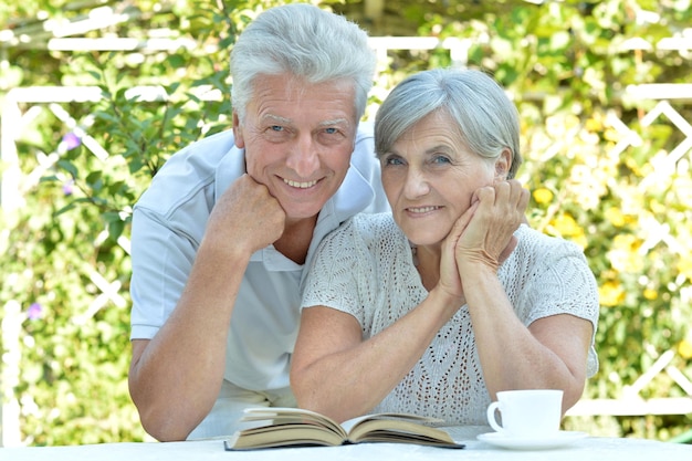 D'âge mûr à une table avec un livre en été