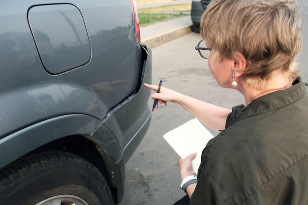 Agent d'assurance femme d'âge moyen effectue l'inspection de pré-assurance de voiture