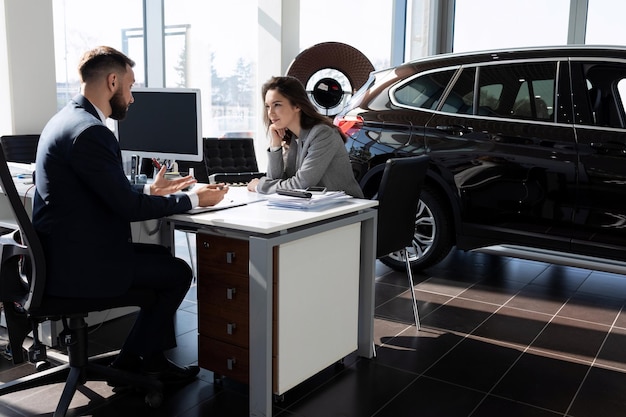 L'agent d'assurance rédige une police à l'acheteur d'une nouvelle voiture dans un concessionnaire automobile