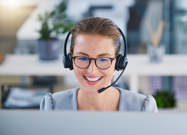 Agent de centre d'appels aidant les clients en ligne tout en parlant sur un casque dans un bureau moderne appréciant sa carrière Service client et assistance avec une femme heureuse et sympathique ravie de guider et de répondre