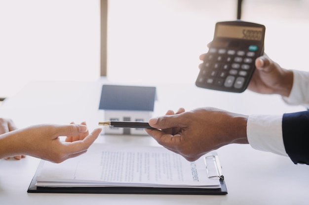 Agent de courtage immobilier présentant et consultant le client pour la prise de décision signant un contrat d'assurance modèle d'achat et de vente de maison concernant l'offre de prêt hypothécaire et l'assurance habitation