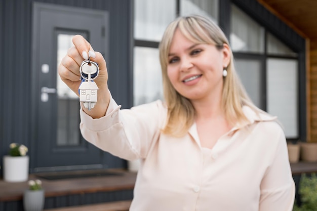 Agent immobilier blond portant les clés de la nouvelle maison d'été offerte par la société de gestion immobilière Immobilier debout avec les clés de la maison de rêve