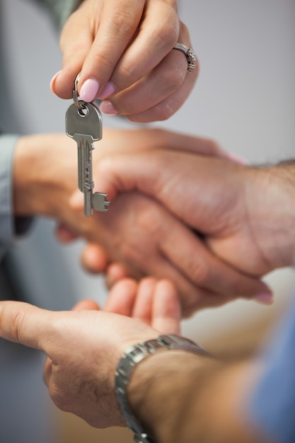 Agent immobilier donnant la clé de la maison au client tout en se serrant la main