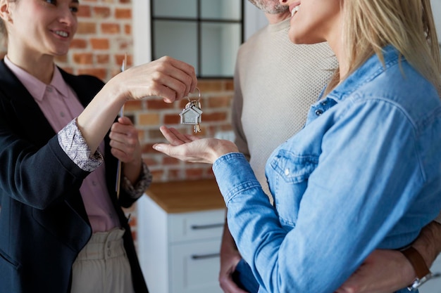 Photo un agent immobilier donne les clés de la maison à un couple.