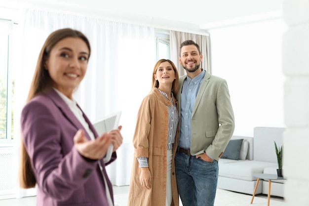 Photo agent immobilier féminin montrant une nouvelle maison à un couple à l'intérieur