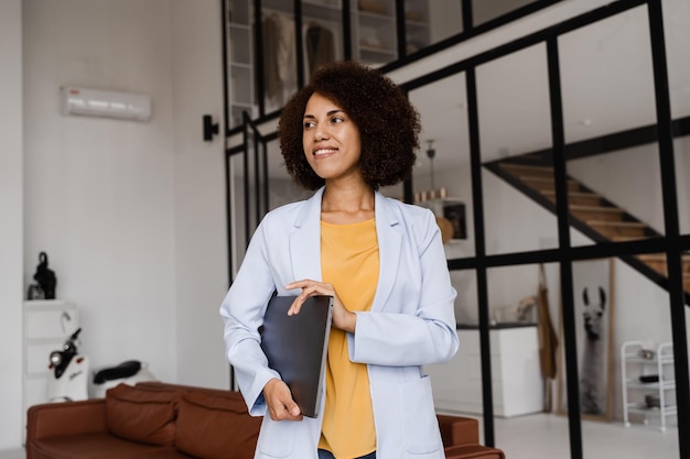 Agent immobilier femme africaine confiante avec ordinateur portable montrant des appartements à louer ou à acheter Hypothèque pour appartement pour les clients Photo créative pour agence immobilière