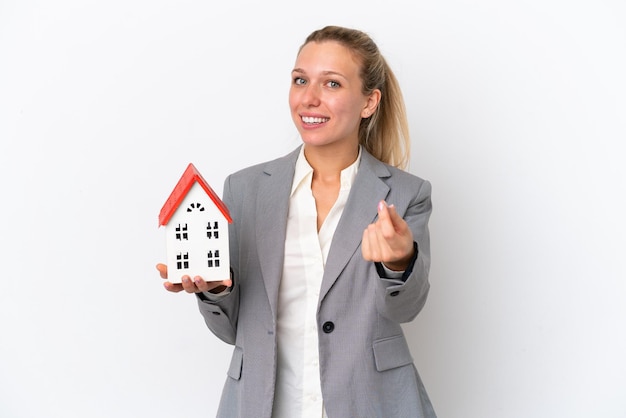 Agent Immobilier Femme Tenant Une Maison De Jouet Isolé Sur Fond Blanc Faisant Un Geste D'argent