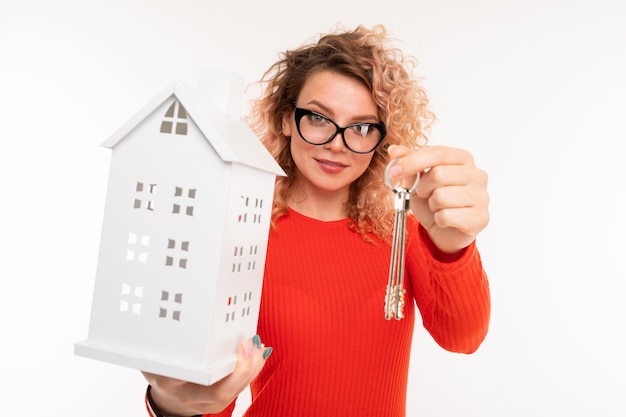 Photo agent immobilier fille tend les clés et un modèle de maison sur blanc