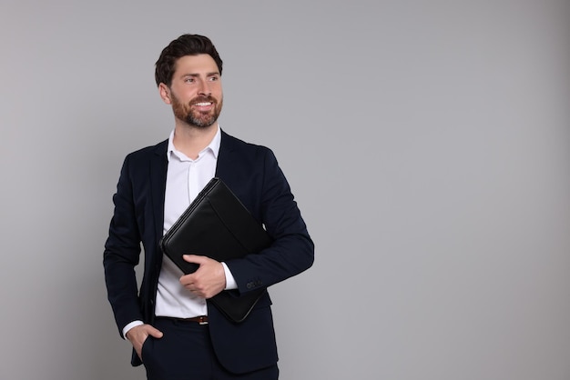 Agent immobilier heureux avec un portefeuille en cuir sur fond gris Espace pour le texte