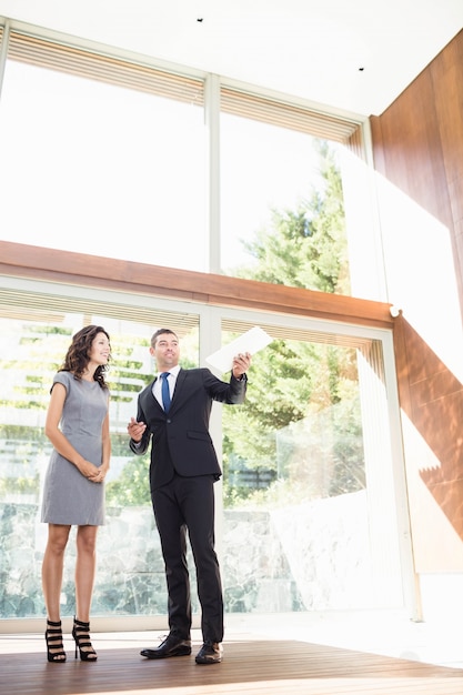 Agent immobilier en interaction avec une jeune femme montrant une nouvelle maison