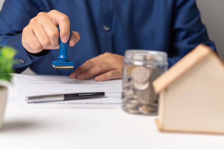 Photo agent immobilier avec maison personne d'affaires tenant un timbre en caoutchouc approuvé sur le contrat de prêt hypothécaire document d'accord plan de la maison sur la table