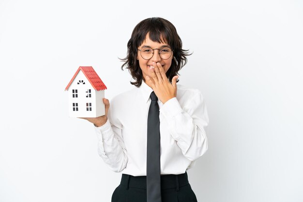 Agent immobilier mixte isolé sur fond blanc heureux et souriant couvrant la bouche avec la main