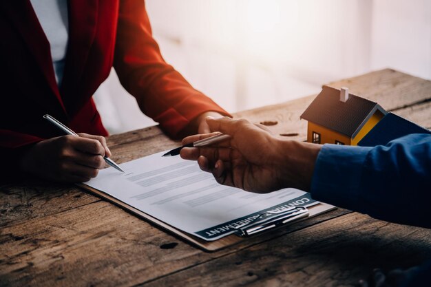 Photo agent immobilier présentant et consultant le client à la prise de décision signer le formulaire d'assurance contrat d'achat et de vente de maison modèle concernant l'offre de prêt hypothécaire et l'assurance habitation