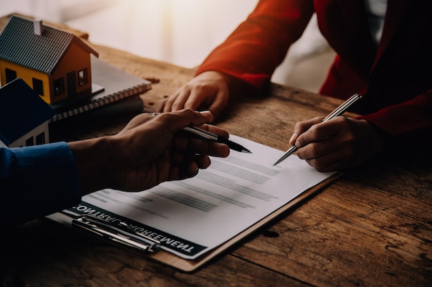 Photo agent immobilier présentant et consultant le client à la prise de décision signer le formulaire d'assurance contrat d'achat et de vente de maison modèle concernant l'offre de prêt hypothécaire et l'assurance habitation