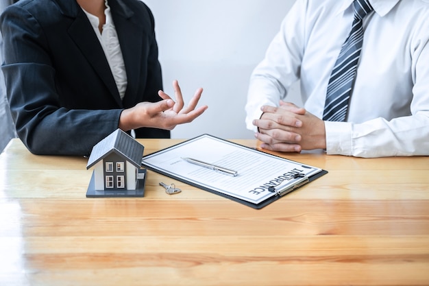 L'agent immobilier présente un prêt immobilier et donne une maison au client après avoir discuté et signé un contrat d'accord avec le formulaire de demande approuvé, l'assurance habitation et le concept d'investissement immobilier.