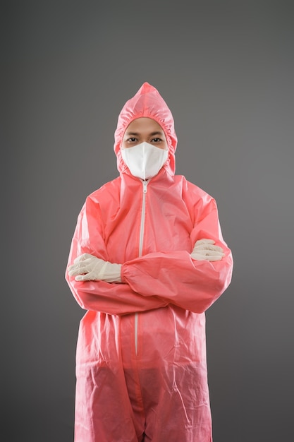 Agent de santé féminin debout avec un portrait de la moitié du corps en ppe rouge et un masque lorsque les mains jointes