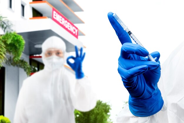 Photo agent de santé femme avec une combinaison de protection et des gants tenant des vaccins covid 19 à l'hôpital