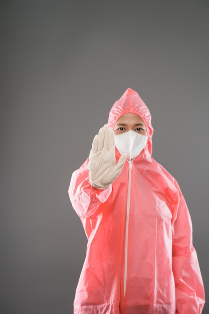 L'agent de santé porte un équipement de protection individuelle avec les paumes vers l'avant comme geste d'arrêt