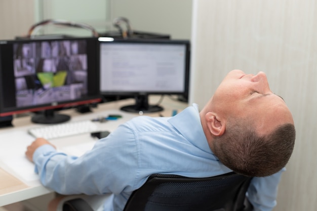 Photo agent de sécurité dormant sur le lieu de travail dans la salle de surveillance