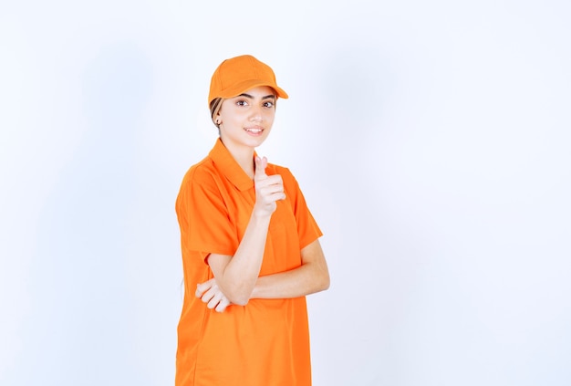 Agent de service féminin en uniforme orange montrant la personne devant