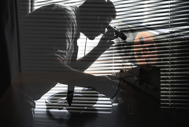 Agent spécial écoute sur le magnétophone à bobines. Officier d'écoutes avec lampe de poche dans les mains. Espionner par la fenêtre. Vieux volets roulants.