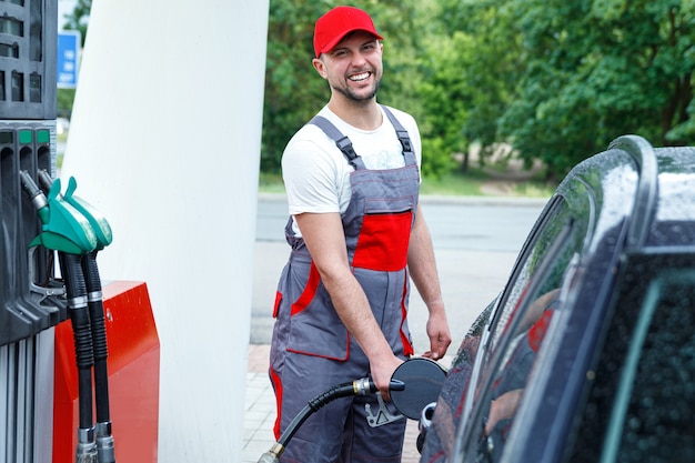 Agent de station-service avec une buse de carburant dans ses mains remplissant le réservoir de la voiture du client