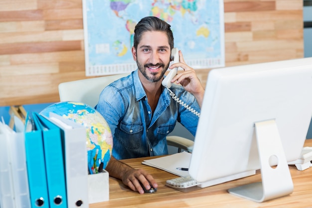 Agent de voyages souriant ayant un appel téléphonique