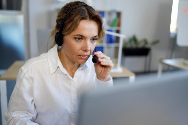 Une agente du centre d'appels avec un casque travaille sur la hotline d'assistance