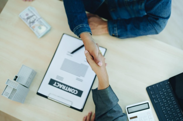 Les agents hypothécaires de la banque serrent la main des clients pour les féliciter après la signature d'un accord de prêt à l'investissement dans le logement