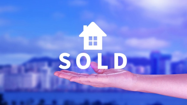 Les agents immobiliers mettent la main avec l'icône maison et mot VENDUE Concept de vente de maison appartement marché immobilier de l'immobilier Investissement immobilier et concept financier d'hypothèque de maison