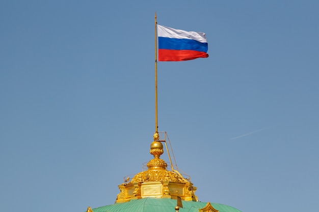 Agitant le drapeau national de la Fédération de Russie sur le dôme du Grand Palais du Kremlin contre le ciel bleu