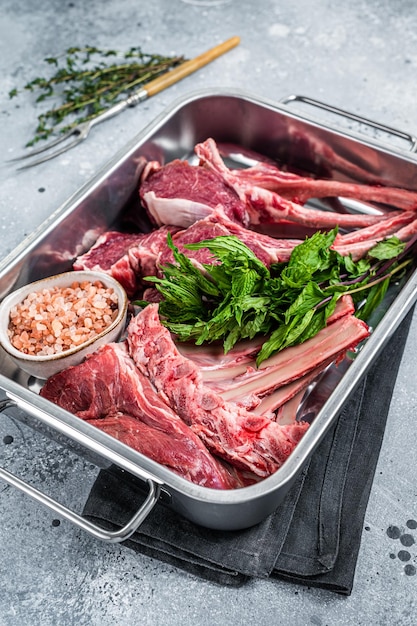 Agneau cru non cuit, côtelettes de mouton dans un plateau de cuisine en acier. Fond gris. Vue de dessus.