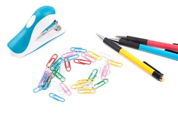 Une agrafeuse bleue et rose à côté d'une paire de trombones et d'un stylo à bille