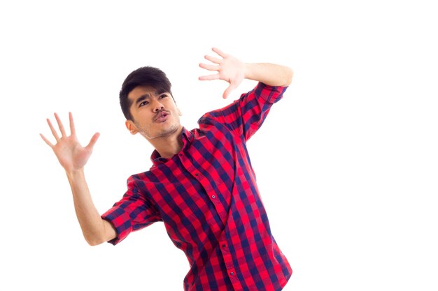 Agréable jeune homme aux cheveux noirs portant une chemise à carreaux rouge sur fond noir blanc en studio