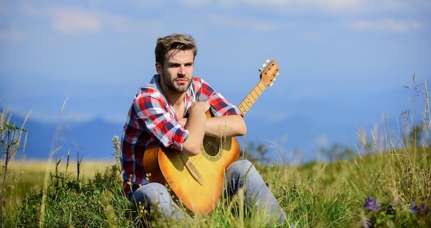 Agréable moment seul Musicien à la recherche d'inspiration Vagabond rêveur Ambiance paisible Un gars avec une guitare contemple la nature Concept Wanderlust Nature inspirante Vacances d'été Hautes terres nature