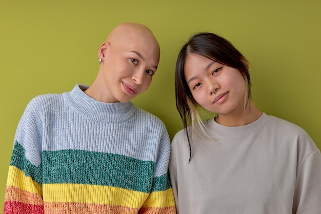 Agréables dames souriantes d'apparence différente posant à la caméra des modèles féminins sympathiques une femme caucasienne souffrant d'alopécie est amie avec une femme chinoise asiatique vêtue d'une tenue décontractée