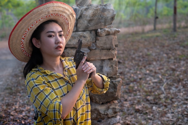 Agriculteur asea woman wearing a yellow shirt hand holding old revolver gun dans la ferme