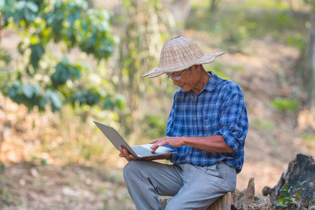 Agriculteur asiatique avec smartphone et ordinateur portable, concept d'entreprise et technologique